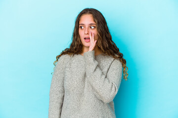 Fototapeta premium Young caucasian curly hair woman isolated is saying a secret hot braking news and looking aside