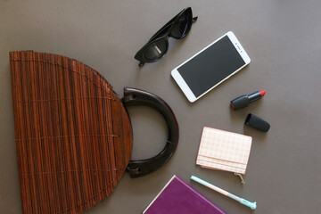 Handbag and content of the bag arranged on gray background. Flat lay.