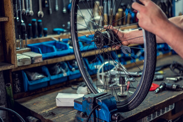Vintage bicycle repair workshop. Man fixing bicycle parts with a wrench working in garage, service...