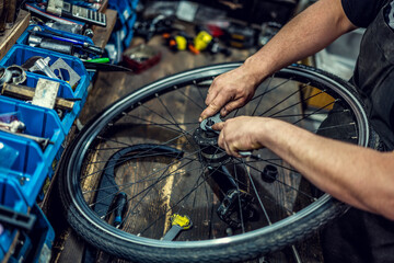 Vintage bicycle repair workshop. Man fixing bicycle parts with a wrench working in garage, service...