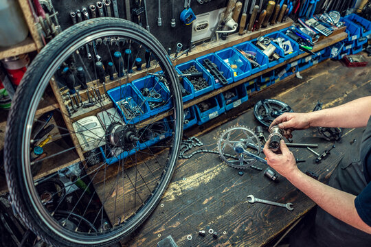 Vintage bicycle repair workshop. Man fixing bicycle parts with a wrench working in garage, service in auto repair station. Bicycle repairing.