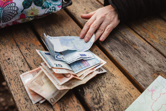 A selective focus shot of euro banknotes on wooden table with man's hand