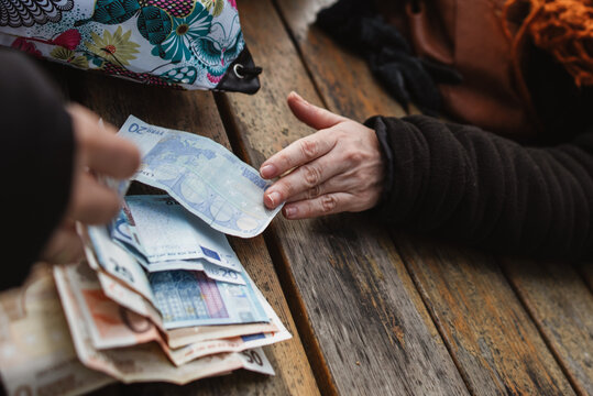 A selective focus shot of euro banknotes on wooden table with man's hand