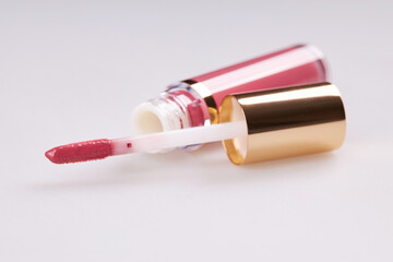 Tube of liquid lipstick gloss with applicator isolated on white background
