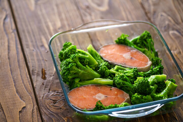 Close-up, dish red fish, salmon and broccoli in glass baking dish. in kitchen