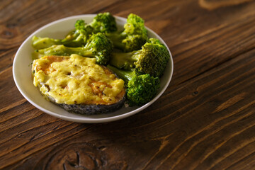 Close-up, a dish of red fish, salmon and broccoli in white plate on wooden table