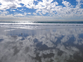 Beach clouds and their reflection on the sand.