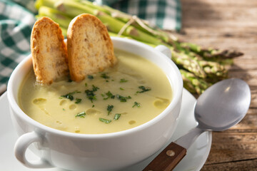 Fresh green asparagus soup in bowl on rustic wooden table