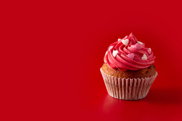 Cupcake decorated with sugar hearts for Valentine's Day on red background. Copy space
