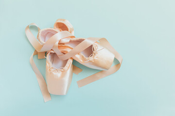 New pastel beige ballet shoes with satin ribbon isolated on blue background. Ballerina classical...