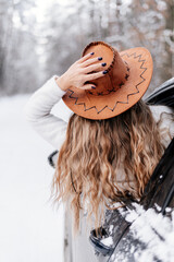 portrait of a woman in a hat in winter forest in black car 