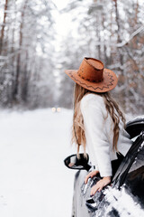 a young girl in a winter forest among the road in the car looks into the distance