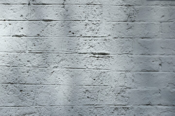 Rough white painted brick wall with shadows.