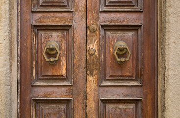 Closeup details and textures on on ancient, brown double door in Cortona, a hill town in the Tuscany region of Italy
