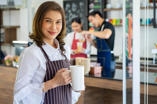 Asian coffee shop owner manager reopen the store after virus pandemic with blurred image of employee