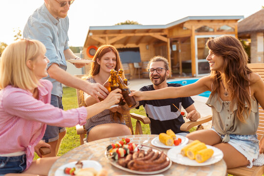 People making a toast at barbecue poolside backyard party