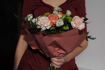 Woman in a burgundy dress holding a bouquet of colorful flowers on a white background to celebrate such holidays as Valentine's Day, Birthday, Mother's Day or International Women's Day. 