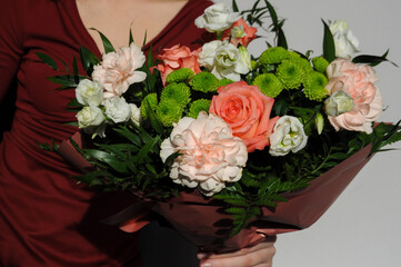 Woman in a burgundy dress holding a bouquet of colorful flowers on a white background to celebrate such holidays as Valentine's Day, Birthday, Mother's Day or International Women's Day. 
