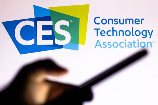 January 20, 2021, Brazil. In This Photo Illustration The Consumer Electronics Show (CES) Logo Seen In The Background Of A Silhouette Hand Holding A Mobile Phone.