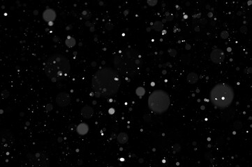 Obraz premium Bokeh of white snow on a black background. Snowfall - design element.