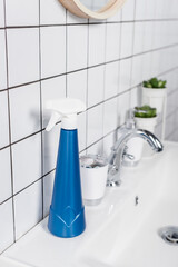 Bottle of detergent with sprayer on sink in bathroom
