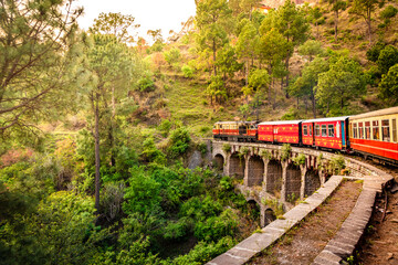 View from moving train on arch bridge over mountain slopes, beautiful view, one side mountain, one side valley. Toy train from Shimla to Kalka in Himachal Pradesh, India