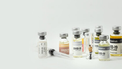 Young man (figurine) standing in empty glass vial with variety of Coronavirus COVID-19 vaccine vials as background.Healthcare And Medical concept.