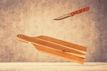 Ein Holzschneidebrett mit einem Messer über einem Holztisch