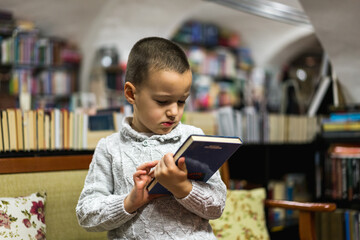 Little child holding book in the library