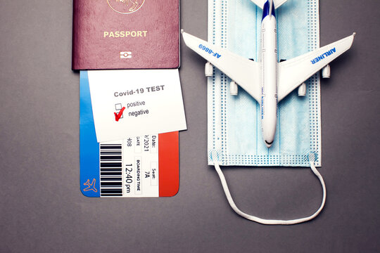 Traveling during COVID-19 virus, passport with airline ticket, covid-19 negative test, medical mask and plane on grey background, airport security health and safety check concept