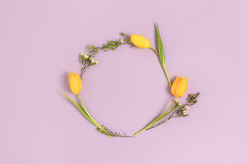 Wreath made of yellow tulip flowers on a purple background. Festive frame with copy space.