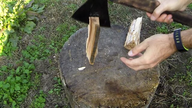 A man cuts a chock into splinters with an axe