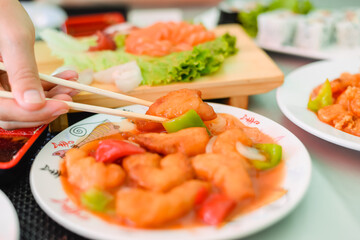 Kid using chopsticks to pick up shrimps isolated on a white background. Healthy eating lifestyle concept.
