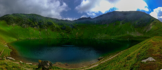 Fototapeta na wymiar clear mountain lake in the middle of green mountains while hiking