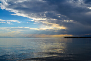 Sunset on lake with beautiful golden clouds and sun rays shining from them.