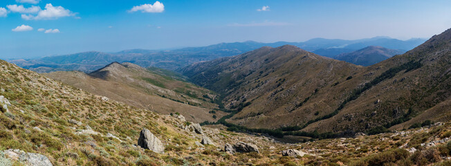 Fototapeta na wymiar Panoramic view from Punta La Marmora highest mountain peak at Gennargentu mountain in Sardinia, Nuoro, Italy. Vaste peaks, dry plains and valleys with mediterranean vegetation. Late summer, blue sky