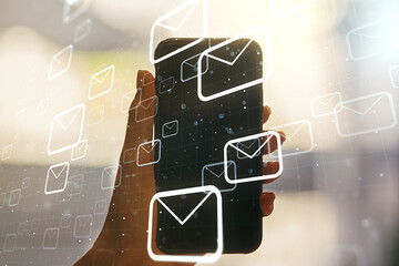 Double exposure of postal envelopes hologram and hand with cell phone on background. Electronic...