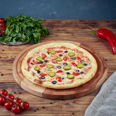 Pizza with meat, vegetables and mushrooms, wooden background