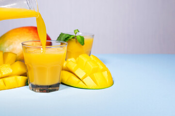Mango Shake on Blue Background. Healthy Drinking Vitamin Smoothie. Fresh Tropical Mango Fruit Juice. Space for Text, Copyspace. Dieting Food. Colourful Background