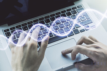 Creative concept with DNA symbol illustration and hands typing on laptop on background. Genome research concept. Multiexposure