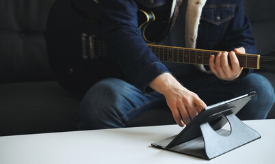 Man learns how to play the guitar. Remote online lesson.