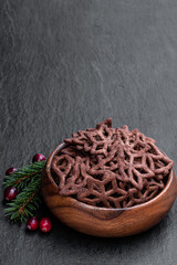 Chocolate pretzel shapes in wooden bowl on black stone background