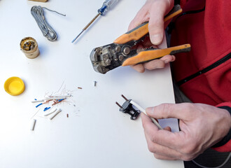 Home hobby. Close-up of a Caucasian man holding a screwdriver, working on an electrician's plug on a white background. switch boron.