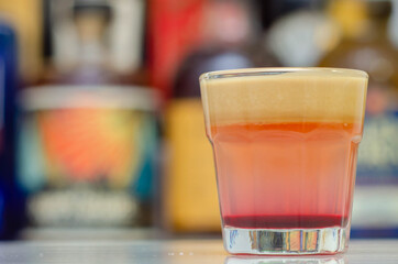 A colorful layered drink shot on a bar prepared by Bartender