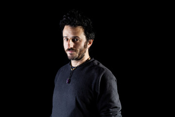 Corridor lighting setup portrait of an adult white man with rock hairstyle and beard looking attractive and confident to the camera. Black background portrait.