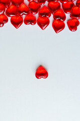 Festive background: lots of red hearts on a white background. Space for the text. Small stones in the shape of a heart.