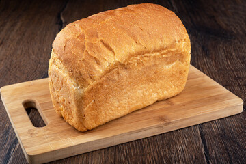Whole loaf of wheat bread on a wooden cutting board.