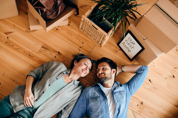 Above view of happy couple relaxing on the floor after buying their first home.