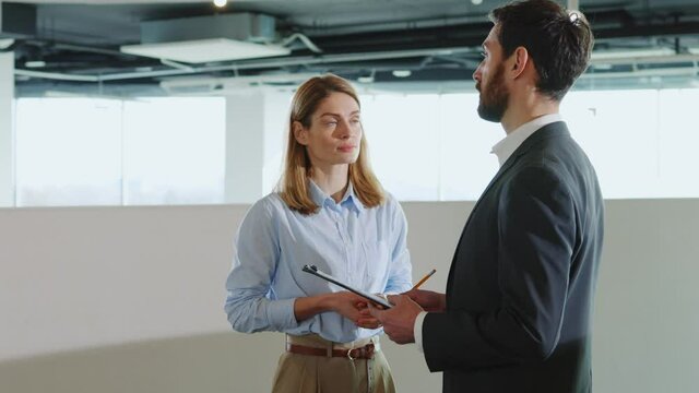 Caucasian corporate business couple of coworkers negotiating in modern enterprise business center working together. Business persons. Cooperation.
