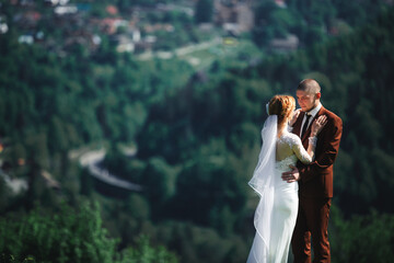 happy stylish bride and groom running and having fun in mountains on summer sunny day. gorgeous newlywed couple laughing, true feelings. emotional romantic moment.
